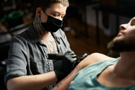 Caucasian tattoo artist drawing on arm of clientの写真素材