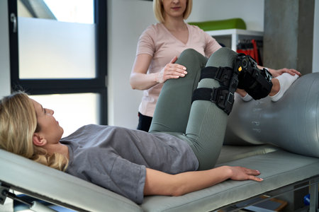 Young woman with orthosis working with physical therapistの写真素材