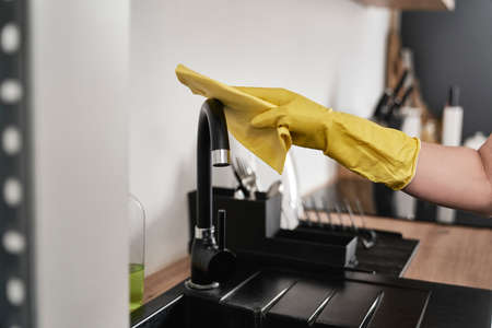 Close up of caucasian woman cleaning tap in kitchen at homeの写真素材