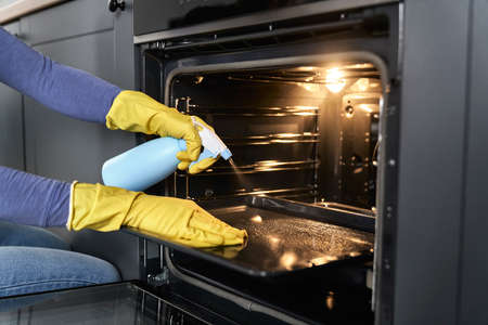Close up of caucasian woman cleaning oven at homeの写真素材
