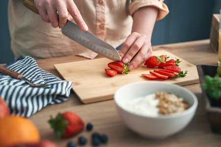 Woman cutting strawberries into slices for a dishの写真素材