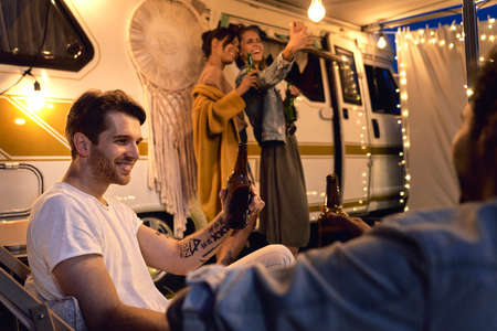 Group of young friends spending time on the camping side in the evening