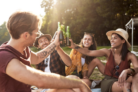 Group of young friends spending time on the camper side on drinking beerの写真素材