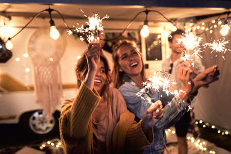 Happy friends enjoying time on camping while holding sparklersの写真素材