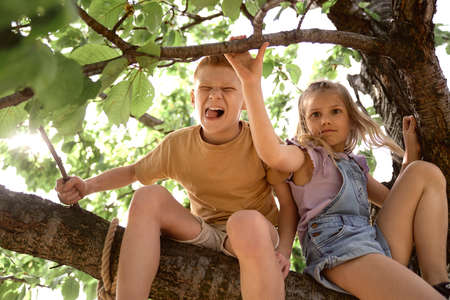 Little kids sitting at the tree at summer day
