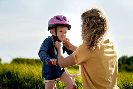 Mother helping fit helmet before bike rideの写真素材