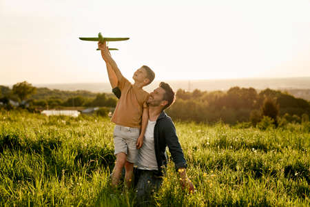 Little boy with father playing a toy airplane at meadowの写真素材
