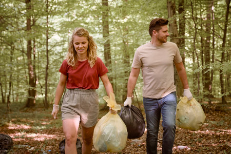 Caucasian adult woman and man holding garbage bag in forestの写真素材