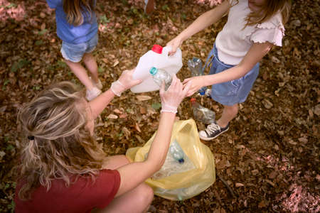 Caucasian family picking up trash to garbage bag from forest