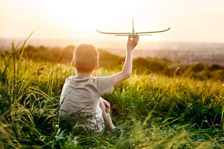 Little boy sitting on the meadow with toy airplaneの写真素材