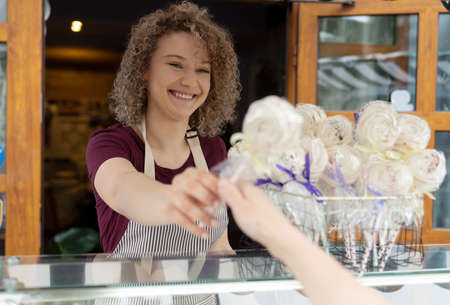Young caucasian woman selling candies out of cafe