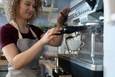 Young caucasian female barista making coffee in the cafeの写真素材