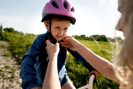 Mother helping fit helmet before bike rideの写真素材