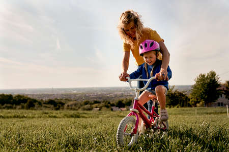 Caucasian woman with toddler learning how to ride bikeの写真素材