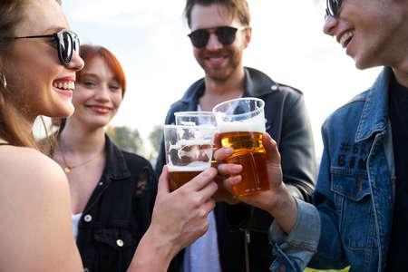 Group of young caucasian friends making toast with beer on music festivalの写真素材