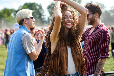 Young woman dancing and having fun on music festival with friends in the background