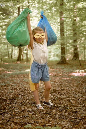 Portrait of little girl warning costume holding plastic bag full of garbagesの写真素材