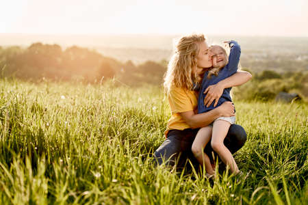 Woman with little girl bonding together at the meadow during the summer sunset