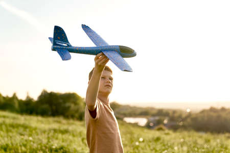 Close up of ginger boy playing toy airplane on the meadow