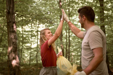 Caucasian adult couple high five with picked up garbages