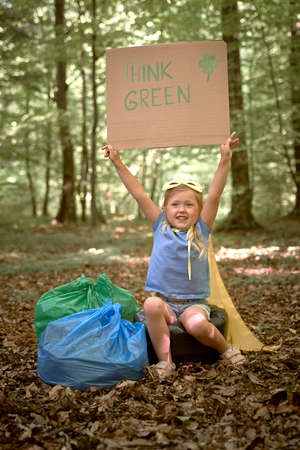 Little girl wearing superhero costume sitting on garbage bagsの写真素材