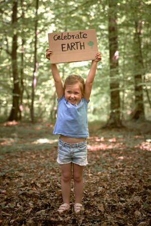 Little caucasian girl holding poster protecting the planetの写真素材