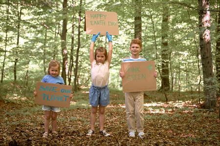 Group of kids holding posters and looking at camera in forestの写真素材