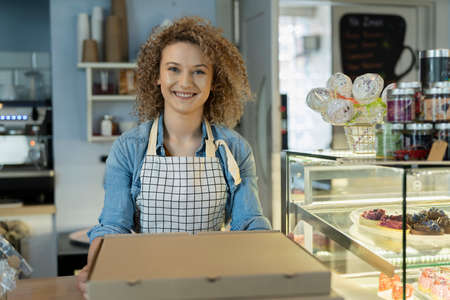 Young caucasian waitress passing take away food towards the camera
