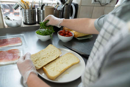 Unrecognizable man preparing a sandwich in commercial kitchenの写真素材