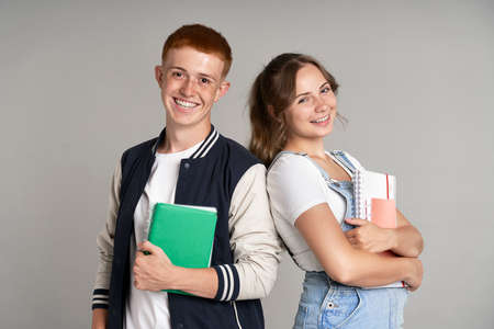 Portrait of smiling girl and boy standing at gray backgroundの写真素材