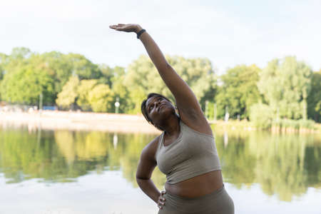 Plus sized African American woman exercising at the park in a summer day