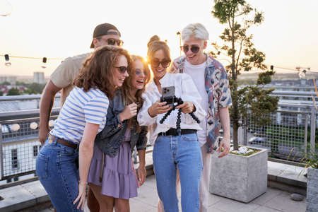 Group of multi ethnicity friends looking at mobile phone at the rooftop partyの写真素材