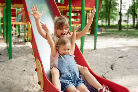 Two cute girls have fun at playground in sunny dayの写真素材