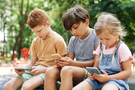 Group of kids using mobile phone at the playgroundの写真素材