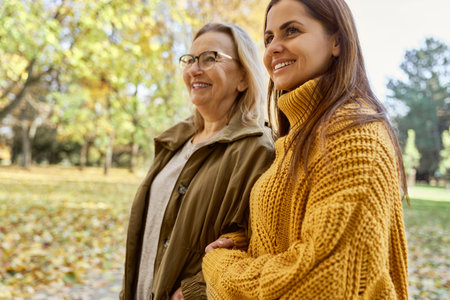 Senior woman with her adult daughter walking at the park during the autumnの写真素材