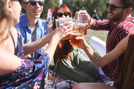 Caucasian friends making toast with beer at music festivalの写真素材