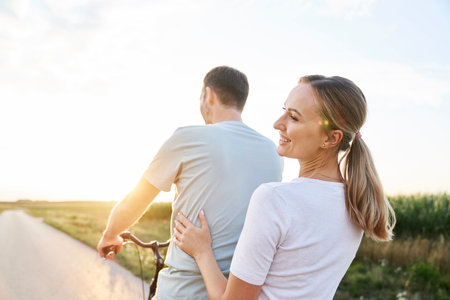 Rear view of caucasian couple having fun on one bike on village roadの写真素材