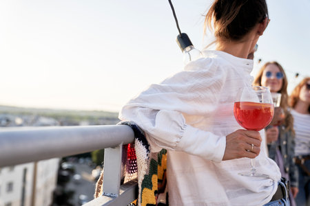 Close up of woman at the rooftop party with cocktail in hand
