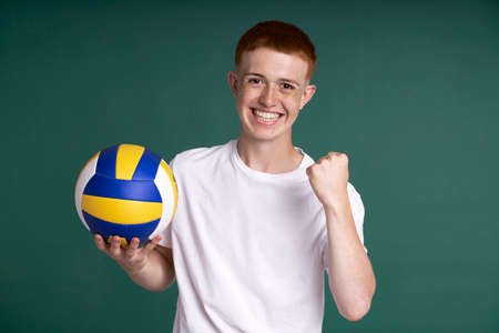 Successful red head boy holding volleyball ball and looking at cameraの写真素材