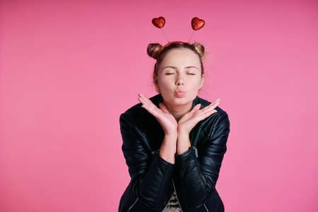 Caucasian teenage girl with heart shape hairband making kiss with eyes closed