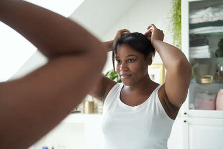 African-American woman checking hair condition in the bathroomの写真素材