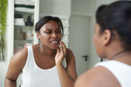 African-American woman in the bathroom having a strong toothache or bruxismの写真素材