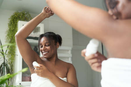 African-American woman feeling fresh while applying roll on antiperspirantの写真素材