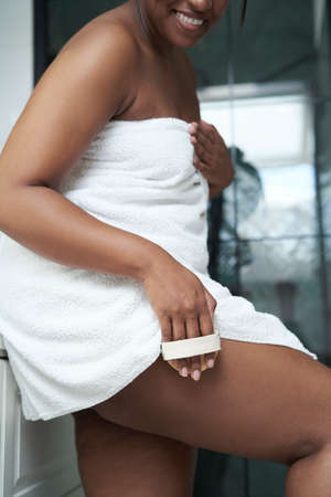 African-American woman scrubbing legs with brush in the domestic bathroomの写真素材