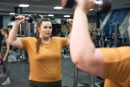 Woman with overweight lifting dumbbells at the gym