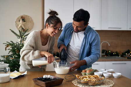 Multi ethnicity couple making a cake together in Christmas timeの写真素材