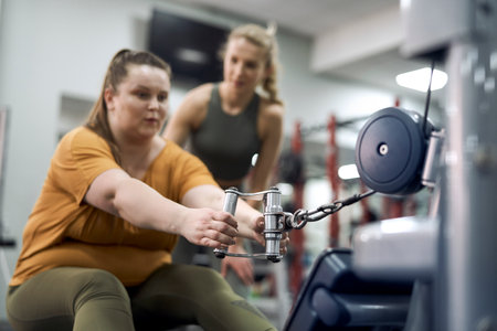 Caucasian plus size woman with her trainer at the gym