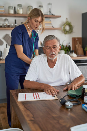 Caucasian female doctor testing senior man at the home visit. Documents prepare special for shoot.の写真素材