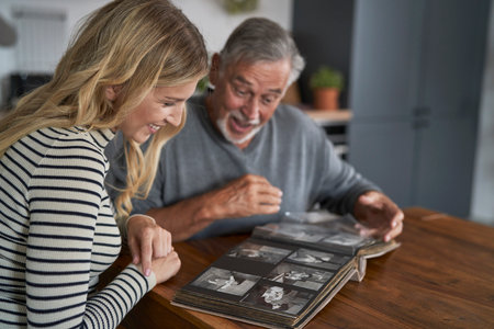 Caucasian woman looking at old pictures in album with senior dadの写真素材
