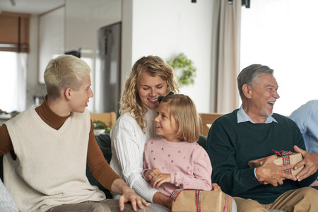 Multi generation caucasian family sitting and holding Christmas presents at home